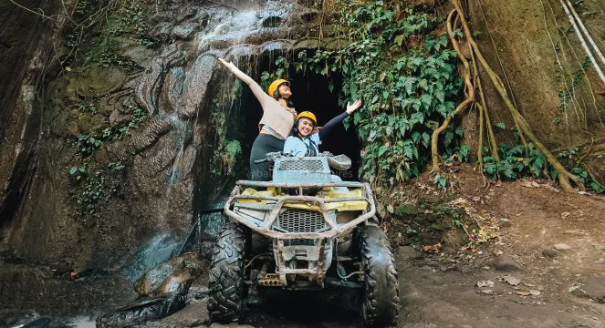 Two tourists posing on a quad bike during a Bali ATV ride adventure near a waterfall cave